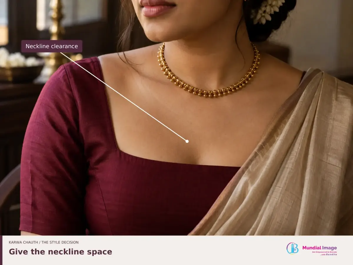 Short gold necklace inside an open wine blouse neckline, with the space above the fabric edge highlighted.